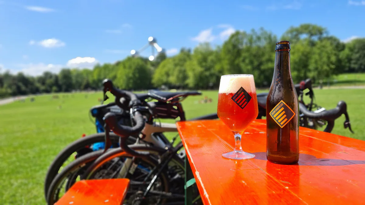 Vandekelder beer and glass on an orange table with bicycles and the Atomium in the background.
